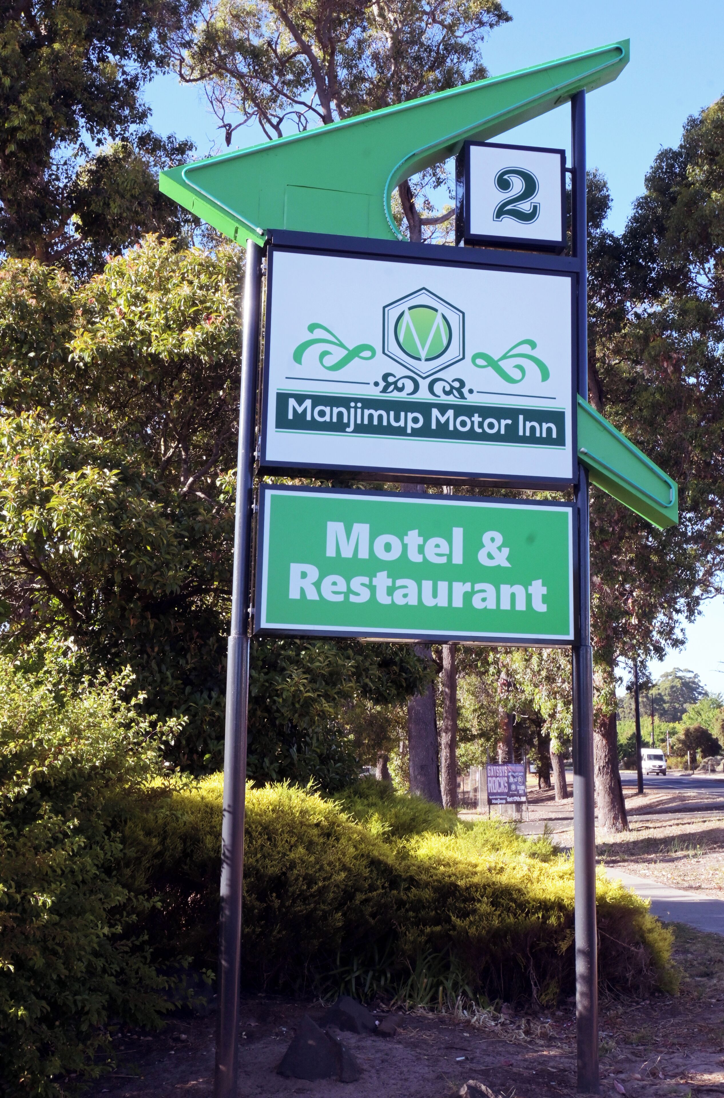 Une enseigne indiquant le « Manjimup Motor Inn », précisant qu’il s’agit d’un motel et d’un restaurant doté d’un toit végétalisé et d’un panneau portant le chiffre « 2 ».