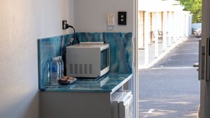 A compact kitchenette with a microwave, a small fridge, and a bench. - Manjimup Motor Inn (Manjimup)