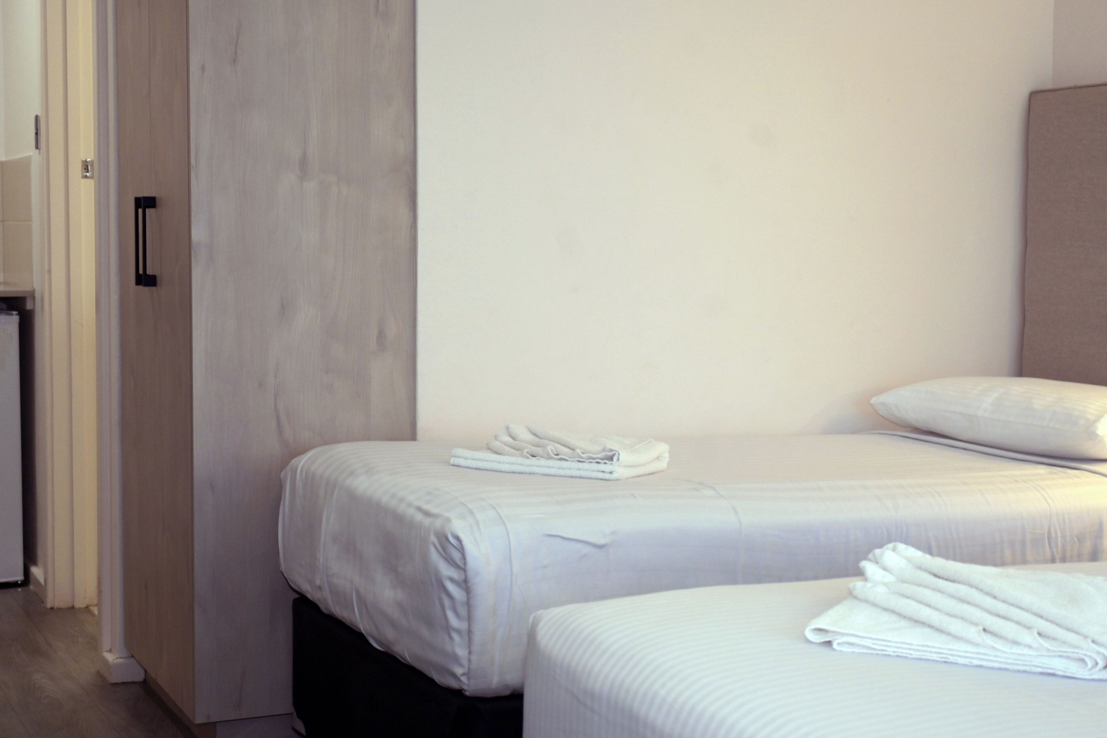 Una habitación de hotel con dos camas, un armario y una mesita.