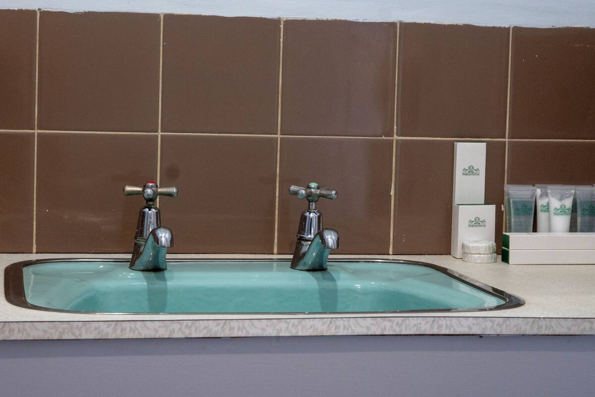 Un bany amb dues aixetes, un lavabo i productes de tocador a la superfície.