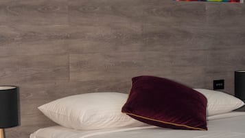A hotel room with two beds, a wooden headboard, a nightstand with a lamp, and artwork on the wall.