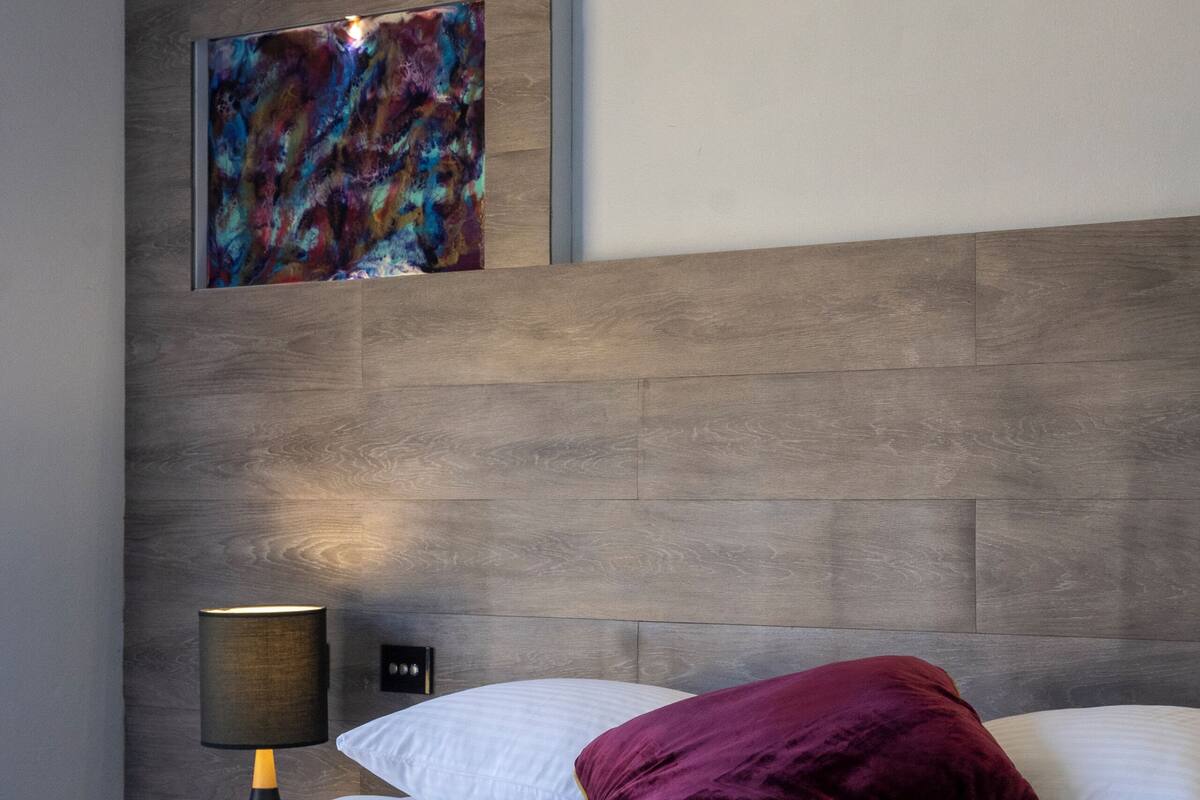 Habitació d'hotel moderna amb un llit gran, una taula de nit, una làmpada i dues obres d'art murals.