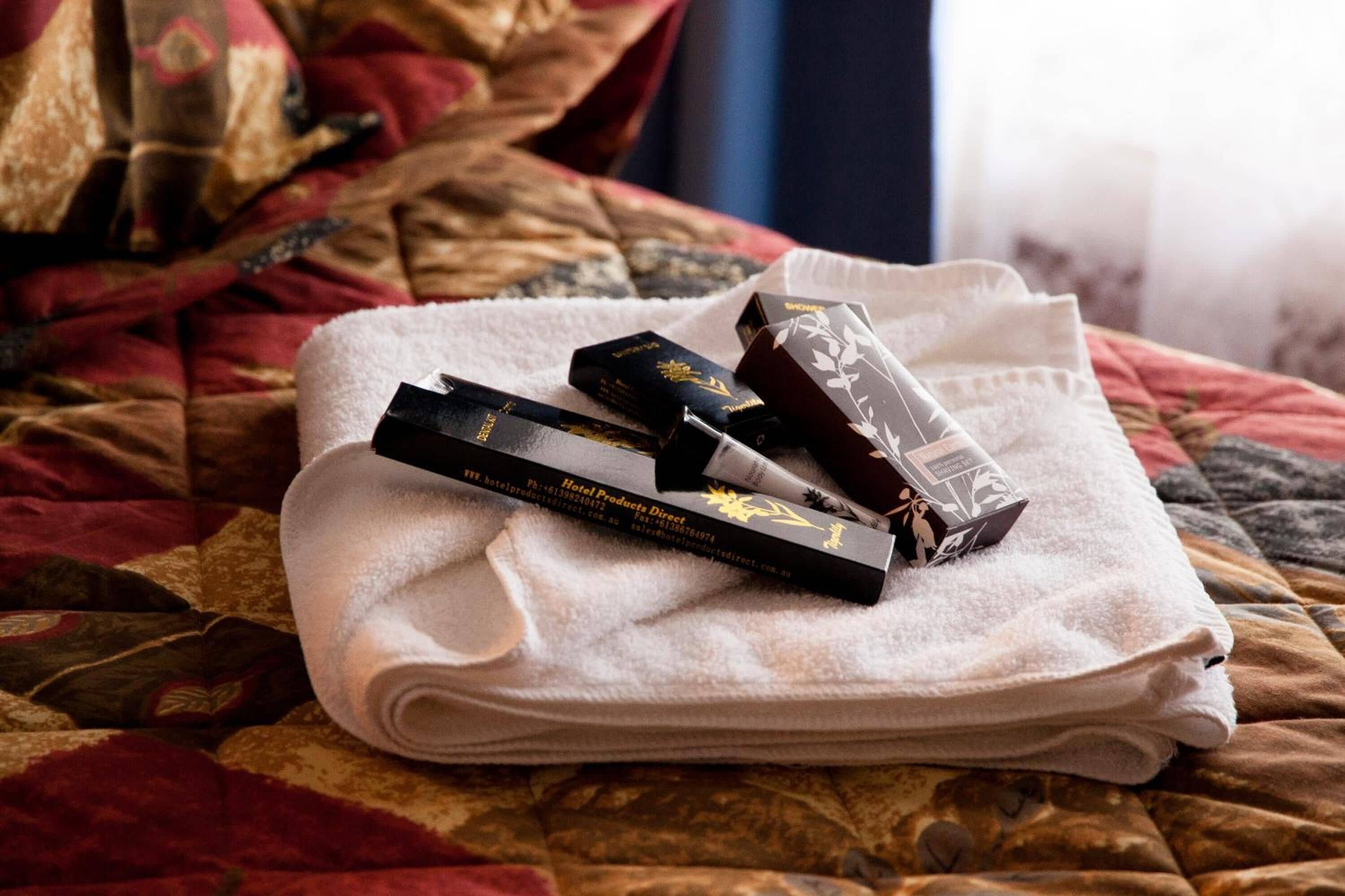 Una toalla blanca doblada con cuidado sobre una cama con colcha estampada.