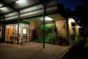 A restaurant with a covered outdoor seating area, brick walls, and potted plants.