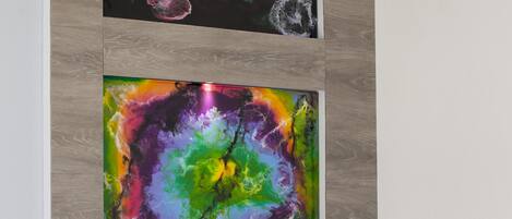 A modern room with a wooden wall, two abstract paintings, a black lamp, and a power outlet.
