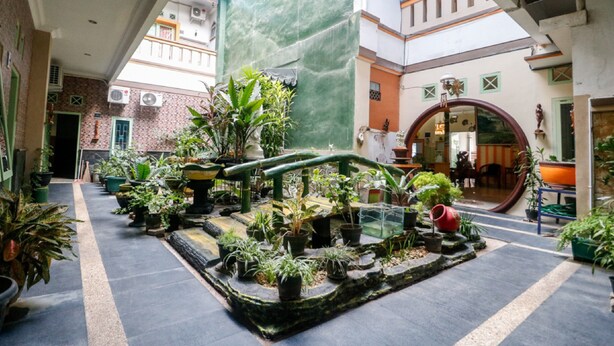 Un amplio atrio con una fuente central rodeado de plantas en macetas.