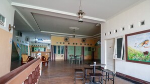 Una habitación amplia con suelo de madera, una zona de comedor con mesas y sillas, y un cuadro grande en la pared.