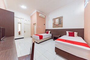 Une chambre d’hôtel avec deux lits, un bureau et une télévision.