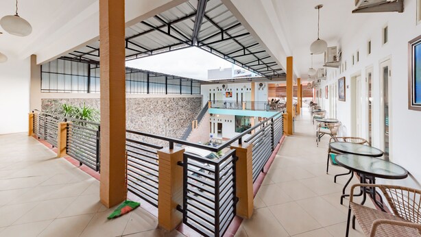 A spacious indoor area with a high ceiling, multiple tables and chairs, and a staircase leading to an upper level.