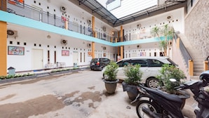 A multi-level building with a central courtyard, featuring a car parking area, potted plants, and a staircase leading to an upper level.