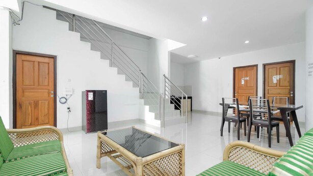 A modern living room with a staircase, green-striped sofas, a glass-top coffee table, and a dining area with chairs and a table.