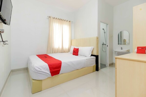 A hotel room with a bed, a bedside table, a mirror, a shower, and a sink.