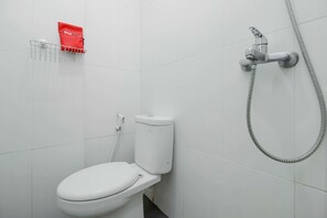 A bathroom with a white toilet, a shower head, and a red bag on a rack.