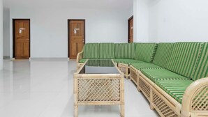 A room with a green-striped sofa, a small wooden table, and two wooden doors.