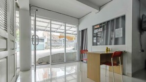 A modern hotel room with a large sliding glass door leading to a balcony, a small desk with a chair, and a view of the outside.