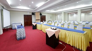 A conference room with a long table, rows of chairs, a projector, and a whiteboard. - RedDoorz Plus @ Singosari Raya (Semarang)