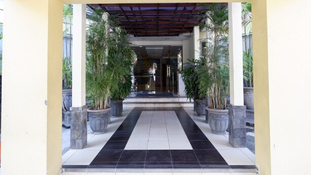 A covered entrance with a tiled floor, potted plants, and a clear view into the building. - RedDoorz Plus @ Singosari Raya (Semarang)