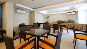 A dining area with tables and chairs, air conditioning units, and a water dispenser. - RedDoorz Plus @ Singosari Raya (Semarang)