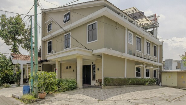 Um edifício de dois andares com varanda coberta, várias janelas e unidade de ar condicionado no telhado.