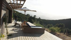 A wooden deck with lounge chairs and umbrellas, overlooking a hilly landscape. - House / Villa - Poggio d''oletta (Poggio-D'oletta)