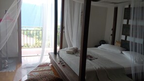 A bedroom with a bed, a bedside table, a chair, and a balcony with a view of greenery. - AURORA Suite apartment Lake Orta-beach00311600048 (pettenasco)