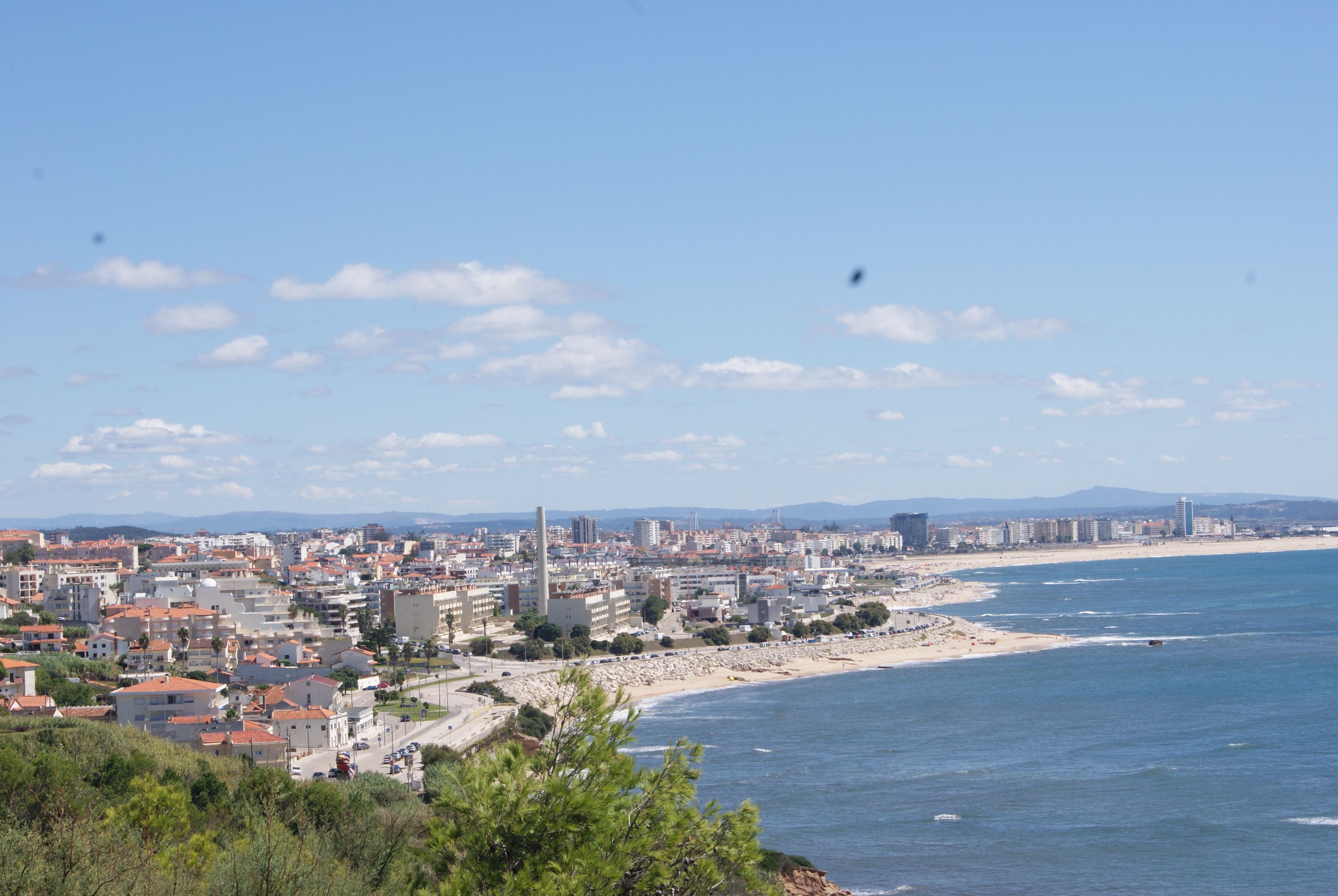 Un paysage urbain côtier avec des bâtiments, une plage et un ciel dégagé.