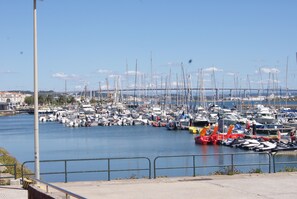 A marina with numerous boats docked, a bridge in the background, and a clear sky.