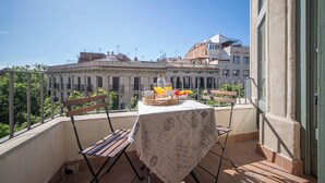 A balcony with a table set for breakfast, a chair, and a view of buildings in the background. - Three bedroom apartment with balcony in Ali Bei - You Stylish (Barcelona)