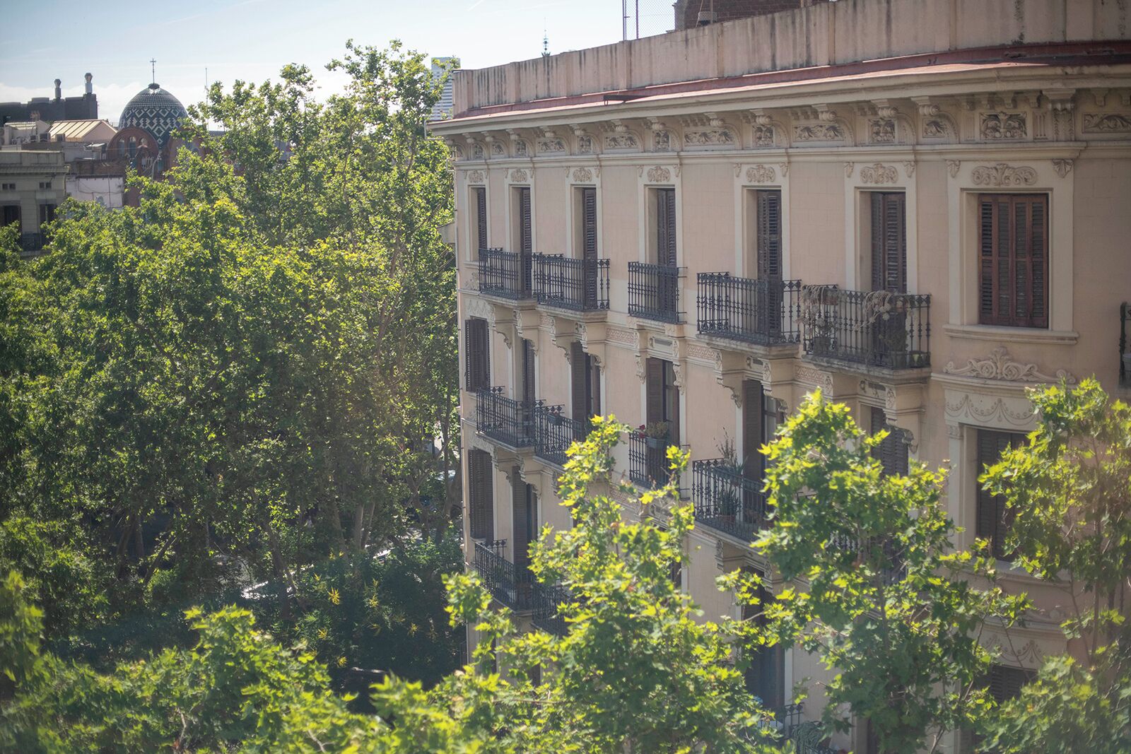 Un immeuble à plusieurs étages, doté de balcons, avec une structure en forme de dôme en arrière-plan.
