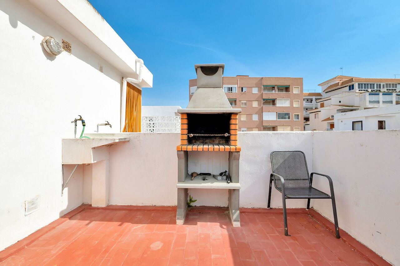 A rooftop with a brick oven, a chair, and a water tap.