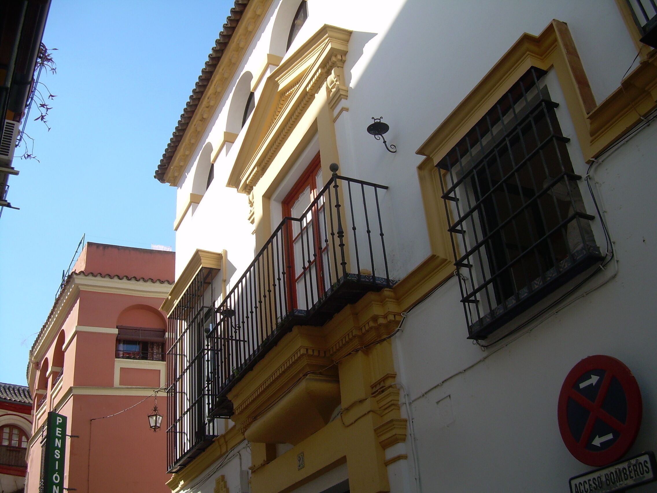 Un edificio con balcón, un cartel de ‘no estacionamiento’ y una placa que indica ‘Pension’.