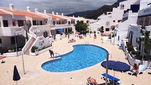 A pool area with a curved pool, sun loungers, and umbrellas.