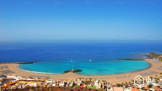 A coastal town with a beach, clear blue sea, and a lighthouse.