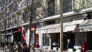 Terrasse de café avec tables et chaises, un panneau indiquant un marché et un restaurant appelé « Cruzcampo ».