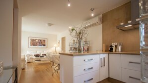 Une cuisine moderne avec des meubles blancs, un îlot central et un coin repas comprenant un canapé blanc et une table basse.