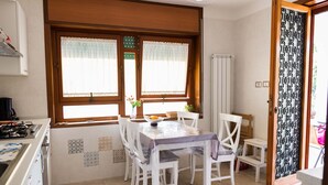 Una cocina con armarios blancos, una estufa y un comedor con mesa y sillas.