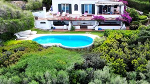 Une vaste villa dotée d’une piscine, entourée d’une végétation luxuriante et située dans un paysage vallonné.