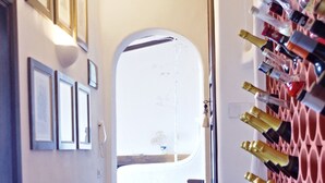 Un couloir avec un escalier menant à une salle de bain, un meuble à vin sur la droite et des tableaux encadrés accrochés au mur.