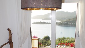 Un coin repas avec une table en bois, une nappe blanche et une vue sur un lac, visible à travers une porte vitrée.