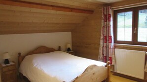 A wooden bed in a room with a window and a radiator.