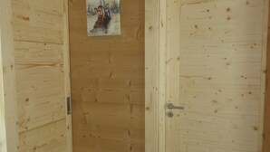 A wooden room with two doors, one with a metal handle and the other with a round doorknob. A small picture hangs on the wall between the doors.