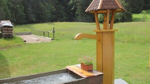 A rustic water pump with a wooden structure and a stone basin.