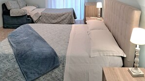 Quarto de hotel com duas camas, uma mesa de cabeceira, uma luminária, um ar condicionado e um quadro na parede.