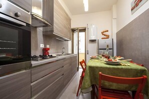 Een moderne keuken met een gasfornuis, roestvrijstalen apparatuur en een eethoek met een tafel voor twee.