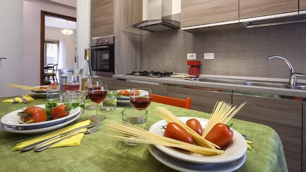 Uma cozinha moderna com armários de madeira, um fogão a gás e um espaço de refeições com mesa posta.