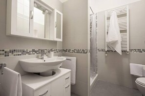 Een moderne badkamer met een witte wastafel, spiegel en douche.