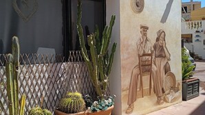 Une façade d’immeuble agrémentée d’un jardin de cactus, d’une décoration en forme de cœur et d’une fresque représentant deux personnages.