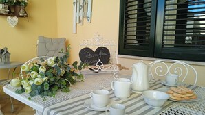 Une table à manger dressée avec des tasses et des soucoupes blanches, une théière et des pâtisseries, ainsi qu’un panneau en forme de cœur sur lequel on peut lire « Samilia et Jerard », et des objets décoratifs accrochés au mur.