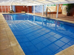 Une piscine intérieure avec un sol carrelé et une eau d’un bleu limpide.