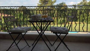 A balcony with a table set for breakfast, two folding chairs, and a view of a park. - Pool, 4 chambres, 4 SdB, clima, cuisine extérieure, grands jardins, aire de jeux (Carpentras)